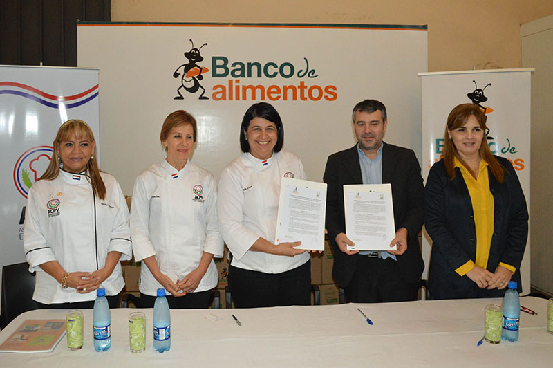 Teresita Benegas O´Hara, presidenta de la Asociación de Chefs del Paraguay y Guillermo Fanego, titular de la Fundación Banco de Alimentos, muestran el convenio firmado. Acompañan Marietta Villamayor y Miryan Vera, de la Asociación de Chefs y Fátima Díaz de Vivar, vice presidenta del Banco de Alimentos