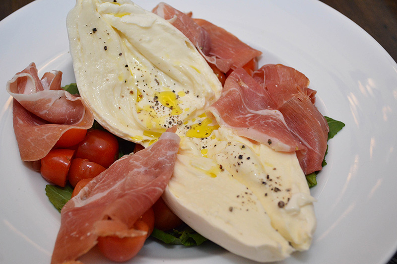 Burrata con jamón crudo, rúcula y tomates cherry, un queso casi desconocido en nuestras mesas que viene para quedarse.