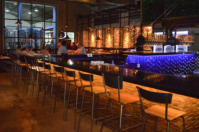 Al fondo se ve la micro cervecería de cerveza. En el primer plano una gran barra en cuyo centro se ubican las canillas que proveen la bebida.