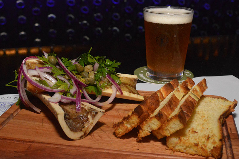 Caracú a la cuchara con toques de cebolla morada, perejil y acompañado de tostadas de focaccia. Maridado con una cerveza Preludio.