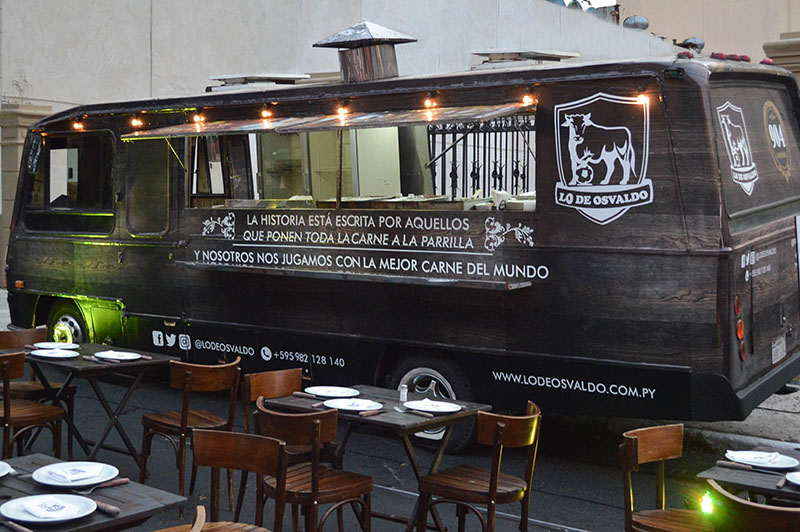 Primer plano del Food Truck. En el interior está equipado convenientemente y afuera se puede la disposición de las mesas y sillas, que también forman parte del servicio.