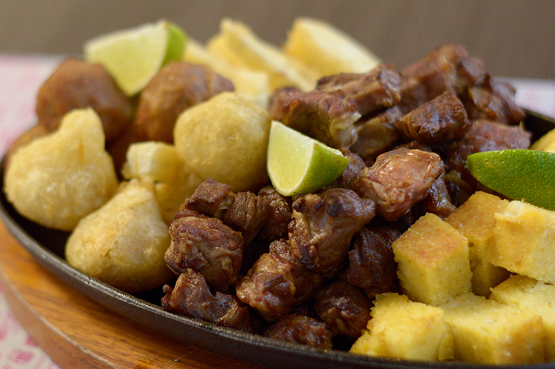 Esta picada es la Coisiña, que lleva coixinha de pollo, entrecostilla, bolitas de carne apanadas y rellenas con queso, mandioca frita y sopa paraguaya.