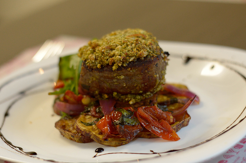 Lomito con Costras de Frutos Secos, que lleva perejil, batata horneada, espinaca, tomates y cebollas asados.