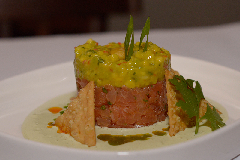 Tartar de salmón. Estilo asiático, aromatizado con aceite de sésamo tostado, palta, emulsión de cilantro y crackers de trigo.