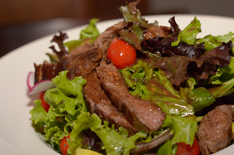 Ensalada Novecento. El plato más emblemático de la franquicia. Lleva tiras de lomito grillado, sobre hojas verdes, plata, tomates cherry y !papas fritas". Aliñado con vinagreta Dijón y salsa demi-glace.