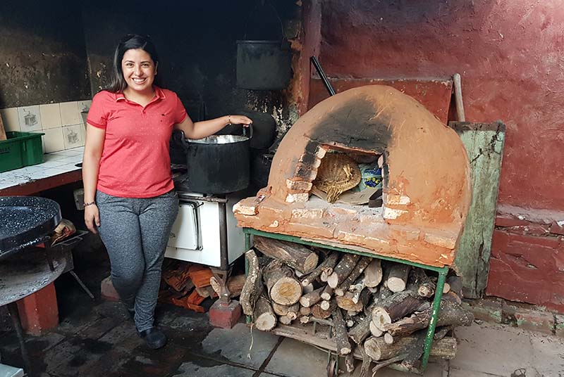 María Liz junto a los elementos de cocina en el fondo de su casa. Un tatakuá, una cocina a leña y a la derecha asoma una especie de paellera. No entraron en el cuadro, las parrillas y el disco de arado.