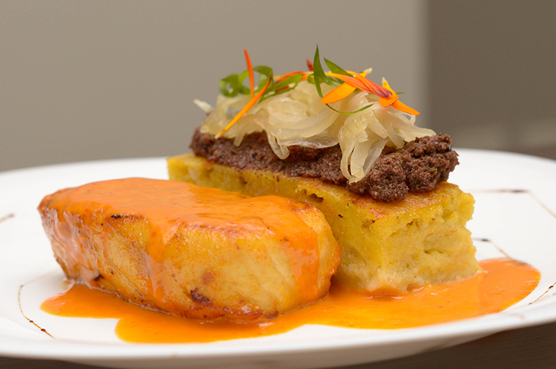 Surubí al horno en salsa de locote rojo y alcaparras, acompañado de sopa paraguaya, tapenade de aceitunas y cebolla caramelizada.