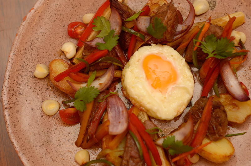 Un lomo saltado a lo pobre. Carne de res salteada al wok con diversas verduras, acompañado de papas y mandiocas fritas.