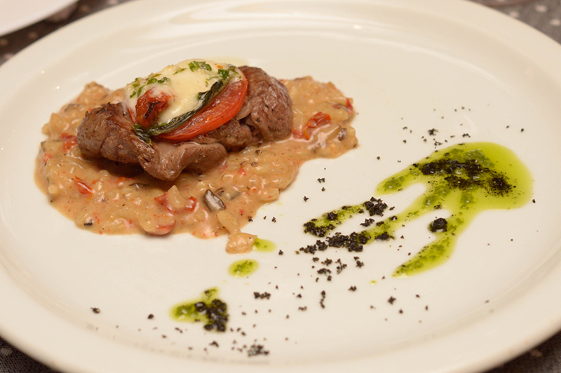 Un medallón de lomito coronado por un toque caprese que tiene tres texturas de tomate, sobre un colchón de risotto al funghi.