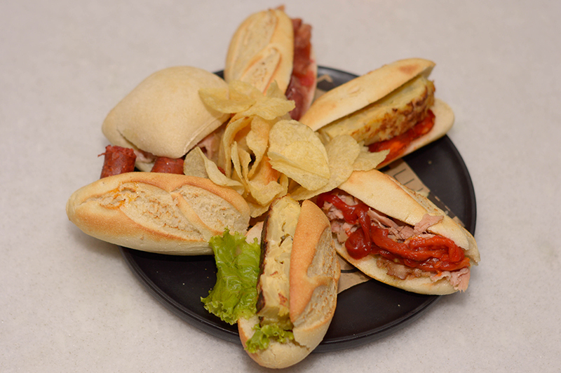 Estos sandwichitos son los montaditos. Los panes son importados de España. Están preparados con diferentes ingredientes. Hay 100 variedades. Aquí vemos el que lleva tortilla de papas, el de chistorra, el de jamón serrano.
