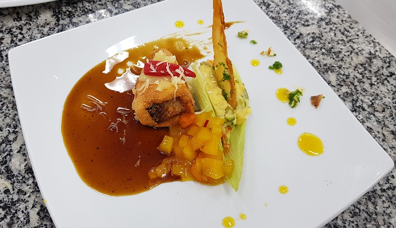 Plato de fondo ganador. Pacú forrado con masa de chipa, ensopado jesuita servido sobre chala de maíz, trozitos de mango confitado, todo sobre un espejo de reducción de cocido al carbón y cachaza. Crocante de mandioca.