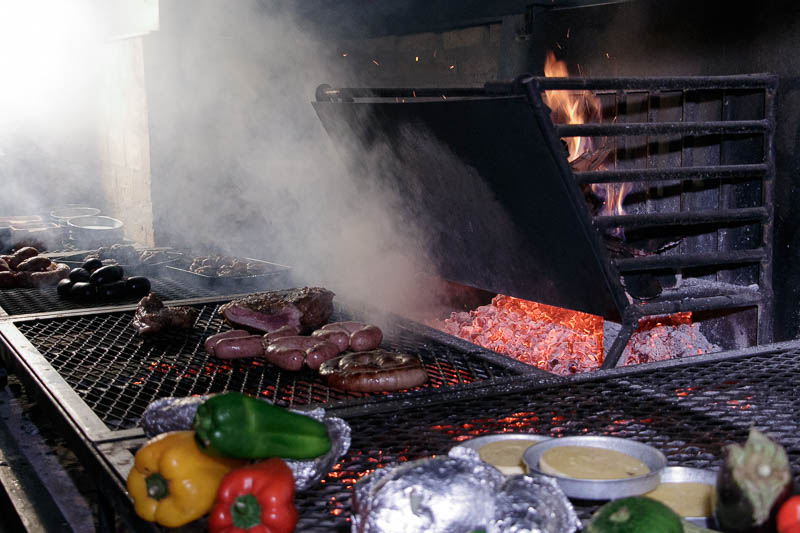 Esto es lo que define a la parrilla uruguaya. Utilizan leña y se cocina con las brasas, en una parrilla hecha con tejido de alambre. Allí van , las carnes, los embutidos, las verduras, el queso provolone, así como las papas y las batatas.