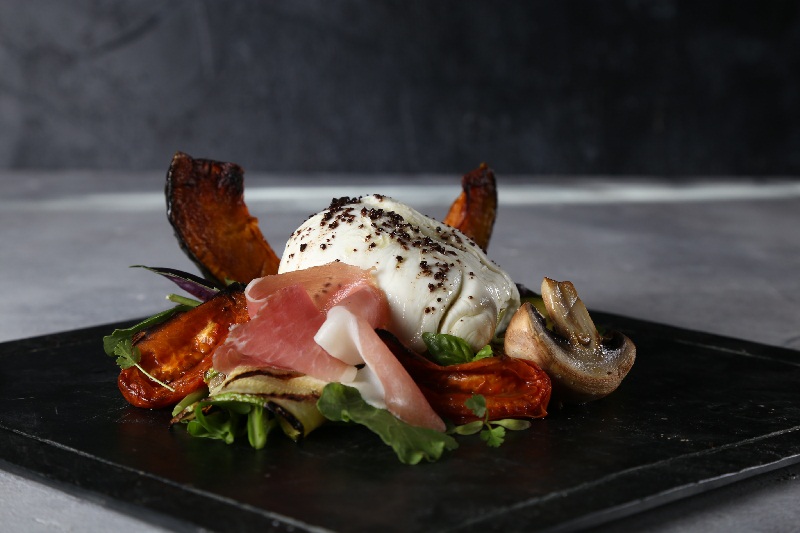 Antipasto italiano. Queso burrata, zapallo asado, polvo de oliva, jamón crudo, rúcula, tomates asados, zuchinis grillados, hongos asados y sal de malbec.