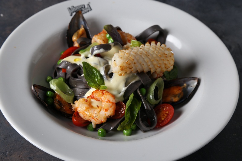 Fetuccine di mare, fetuccine con tinta de calamar, langostinos, mejillones, puerro, tomates cherry, arjeas, salsa Alfredo y pesto de rúcula.