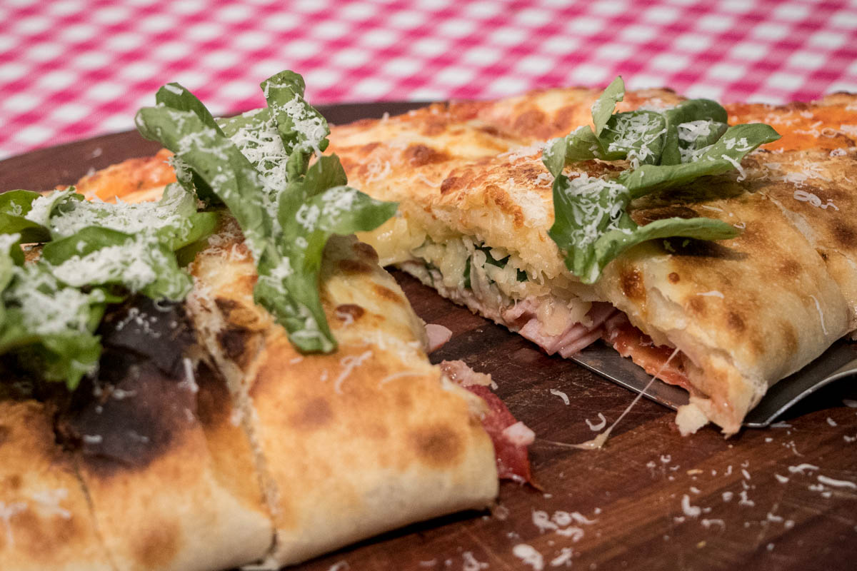 Apetitosa imagen del calzone. Vale la pena. También hay ofertas de lomitos, hamburguesas y bifes. De beber, variadas marcas de cerveza y alguno que otro vino.